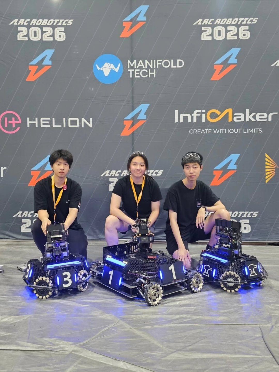 Our three team members kneeling behind our three robots at ARC Robotics 2026