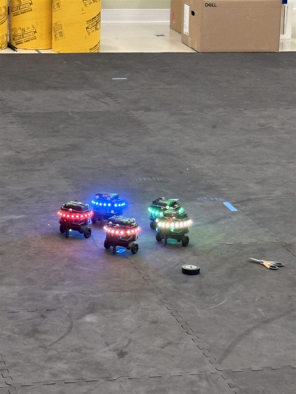 Five differential-drive swarm robots with LED rings in the OptiTrack arena